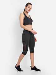 Waylene's black sports bra and Capri set for active women. Model poses with one hand on hip and the other slightly extended, highlighting the breathable fabric and body-hugging fit of the outfit.