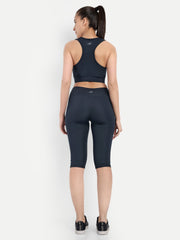 ALT text: Rear view of a model in Waylene's navy blue capri tights and sports bra, showcasing the seamless stitching and logo placement.
