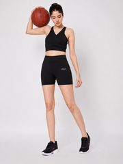 Full-length view of model holding a basketball wearing Waylene black sports bra and matching activewear shorts