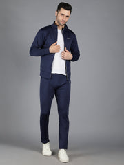 Waylene's navy blue slimfit training sweatshirt and trackpant set, featuring a model with the jacket unzipped to reveal a white T-shirt. The model poses confidently with his hand adjusting the sweatshirt's collar.