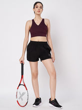 Waylene's black polyester shorts worn by a female model holding a tennis racket, paired with a maroon sports bra and black athletic shoes, ideal for sports and active lifestyles.