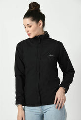 Waylene's black waterproof jacket featuring a full-zip front, high collar, and embroidered logo on the chest, modeled by a woman in a casual stance with her hands in her jeans pockets.