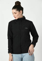 Waylene's black waterproof jacket featuring a full-zip front, high collar, and embroidered logo on the chest, modeled by a woman in a casual stance with her hands in her jeans pockets.