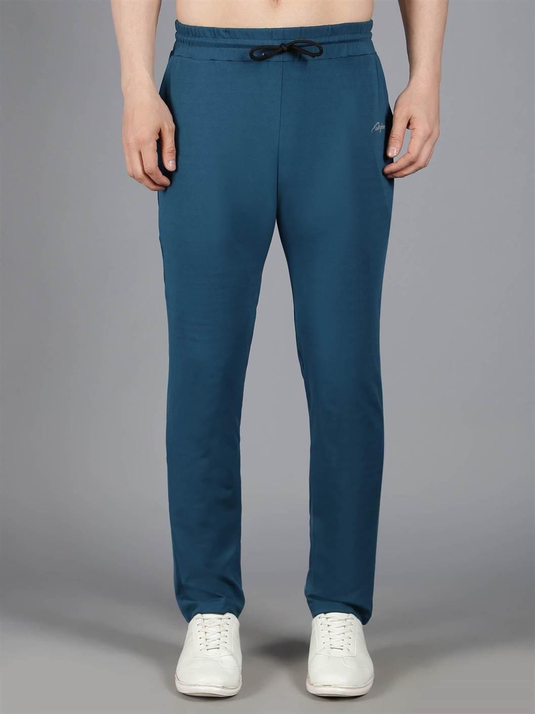 Waylene's teal blue solid trackpant, front view on a male model with hands on hips, paired with white sneakers.