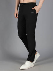 Model showcasing Waylene's black solid trackpant with a slim fit and Waylene script logo on the left thigh, hands partially in pockets, posed against a neutral gray backdrop.