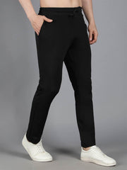 Man modeling Waylene's black trackpant, highlighting a tapered fit and smooth fabric, standing with one hand in pocket on a gray background.