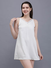 Waylene's simple and elegant white cami nightdress showcased by a model standing with one hand on her hip, detailed with delicate lace trim around the neckline.
