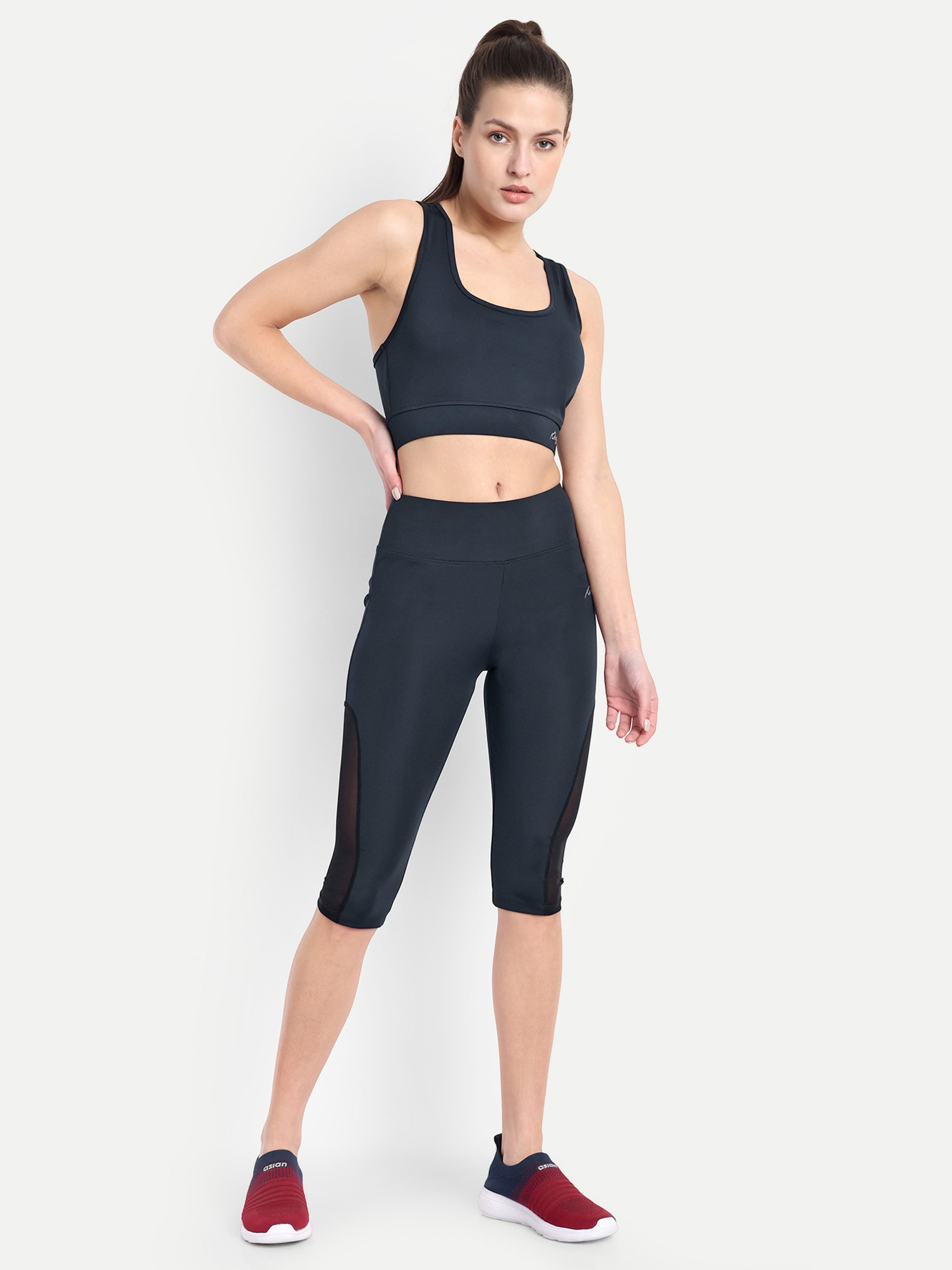 Woman posing in Waylene navy blue high-waisted sports capris with mesh panels and sports bra.