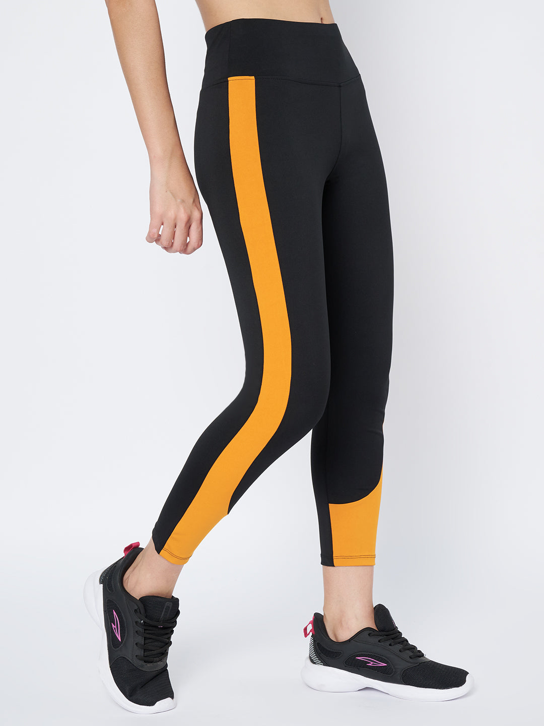Side view of Waylene's high-performance black and mustard gym tights for women highlighting the elongated mustard stripe down the leg, ideal for running or gym workouts.