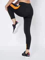 Rear view of Waylene's high-performance black and mustard gym tights for women, emphasizing the snug waistband and curve-enhancing design, perfect for high-intensity workouts.