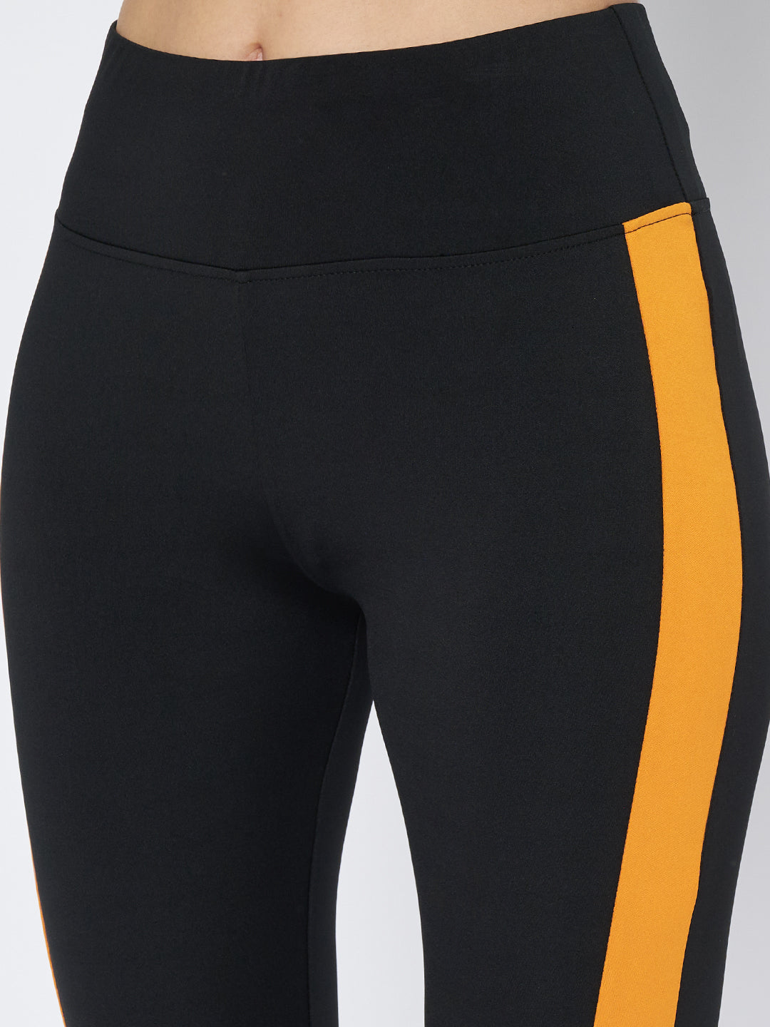 Close-up of the hip and thigh section of Waylene's high-performance black and mustard gym tights for women, showcasing the precision of the stripe alignment and fabric quality.