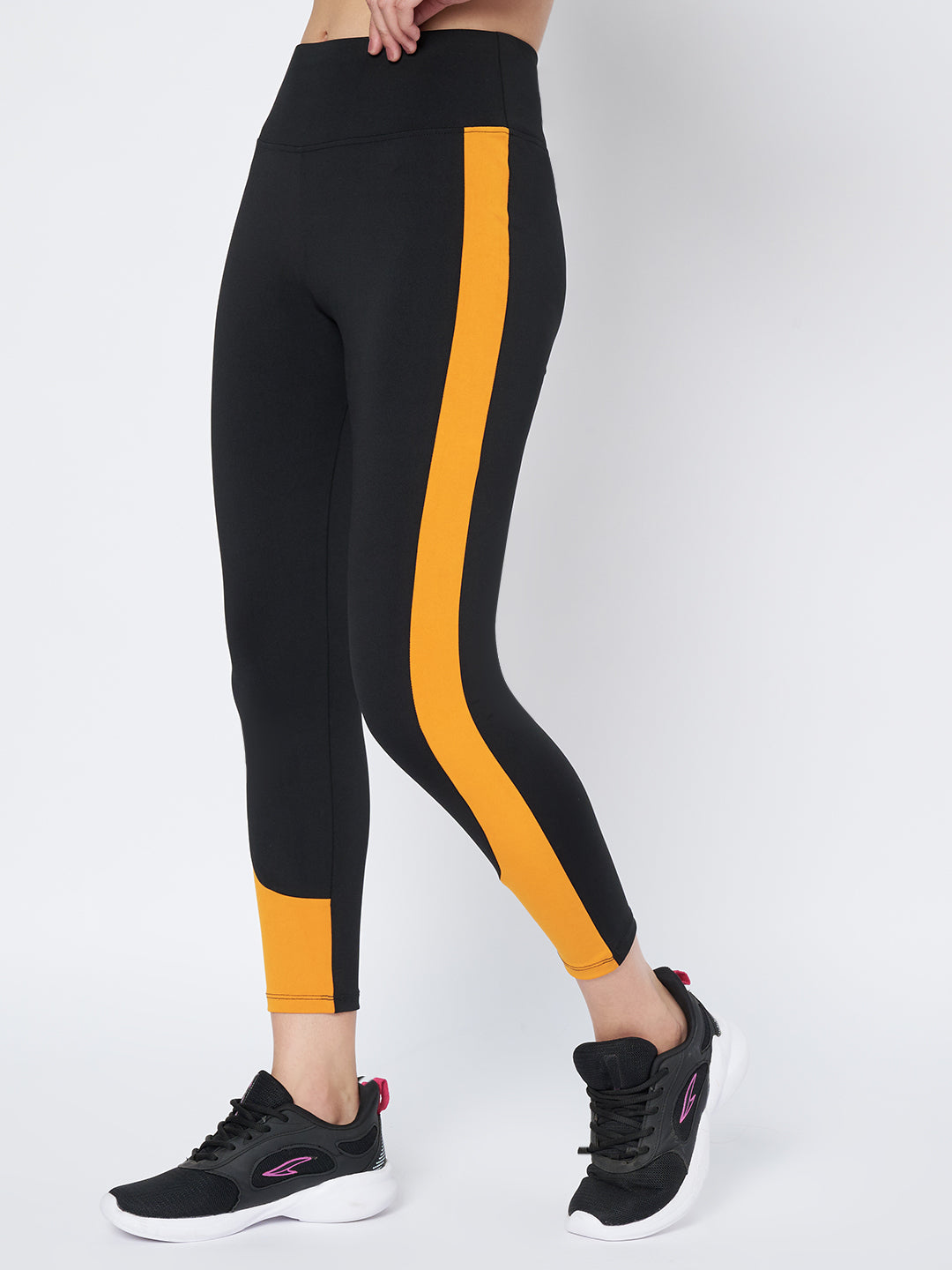 Dynamic side view of Waylene's high-performance black and mustard gym tights for women, emphasizing the contouring lines and active fit, suitable for fitness enthusiasts.