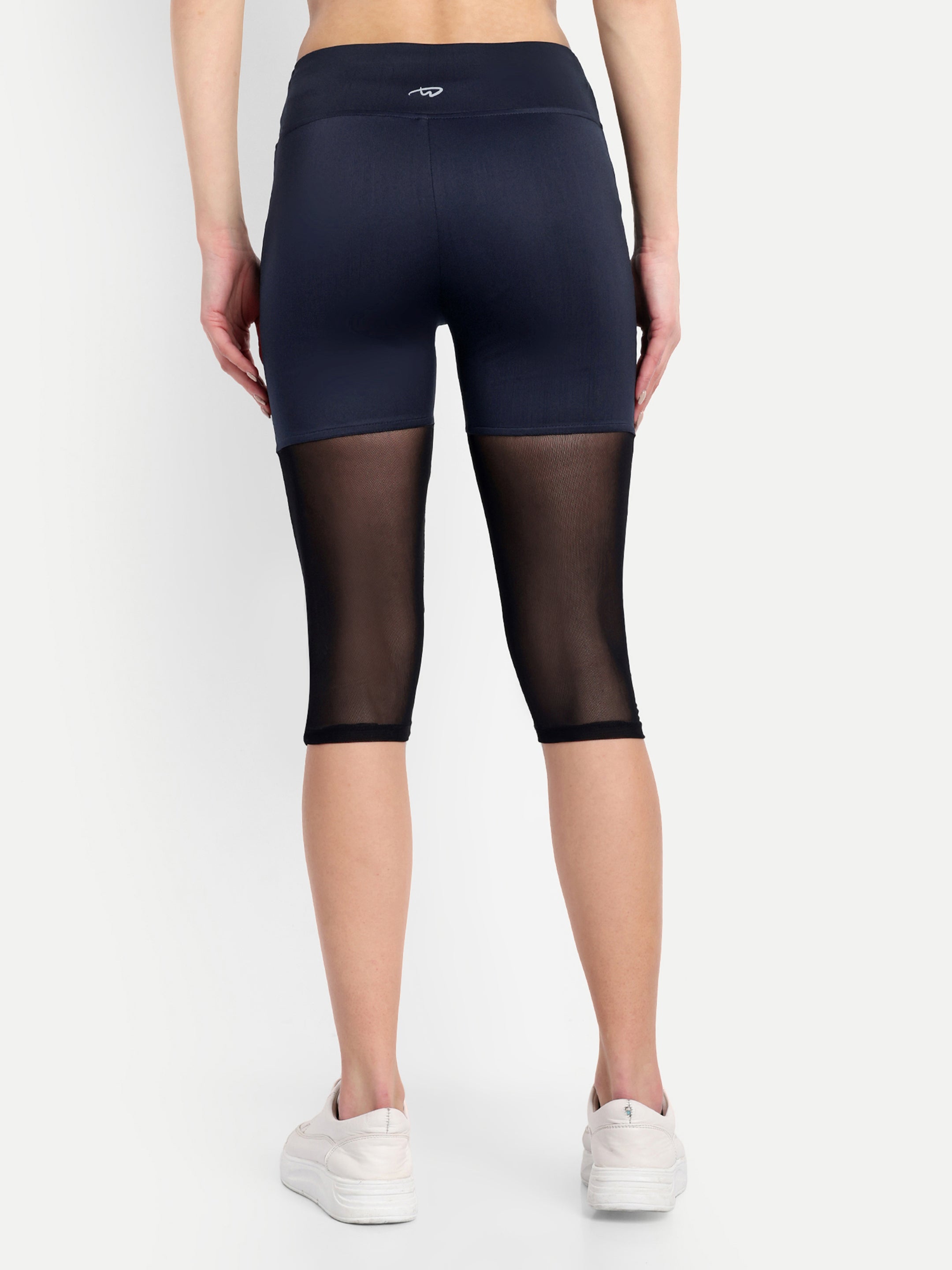 Woman wearing  Waylene navy blue high-waisted capri leggings with rounded mesh panels – back view