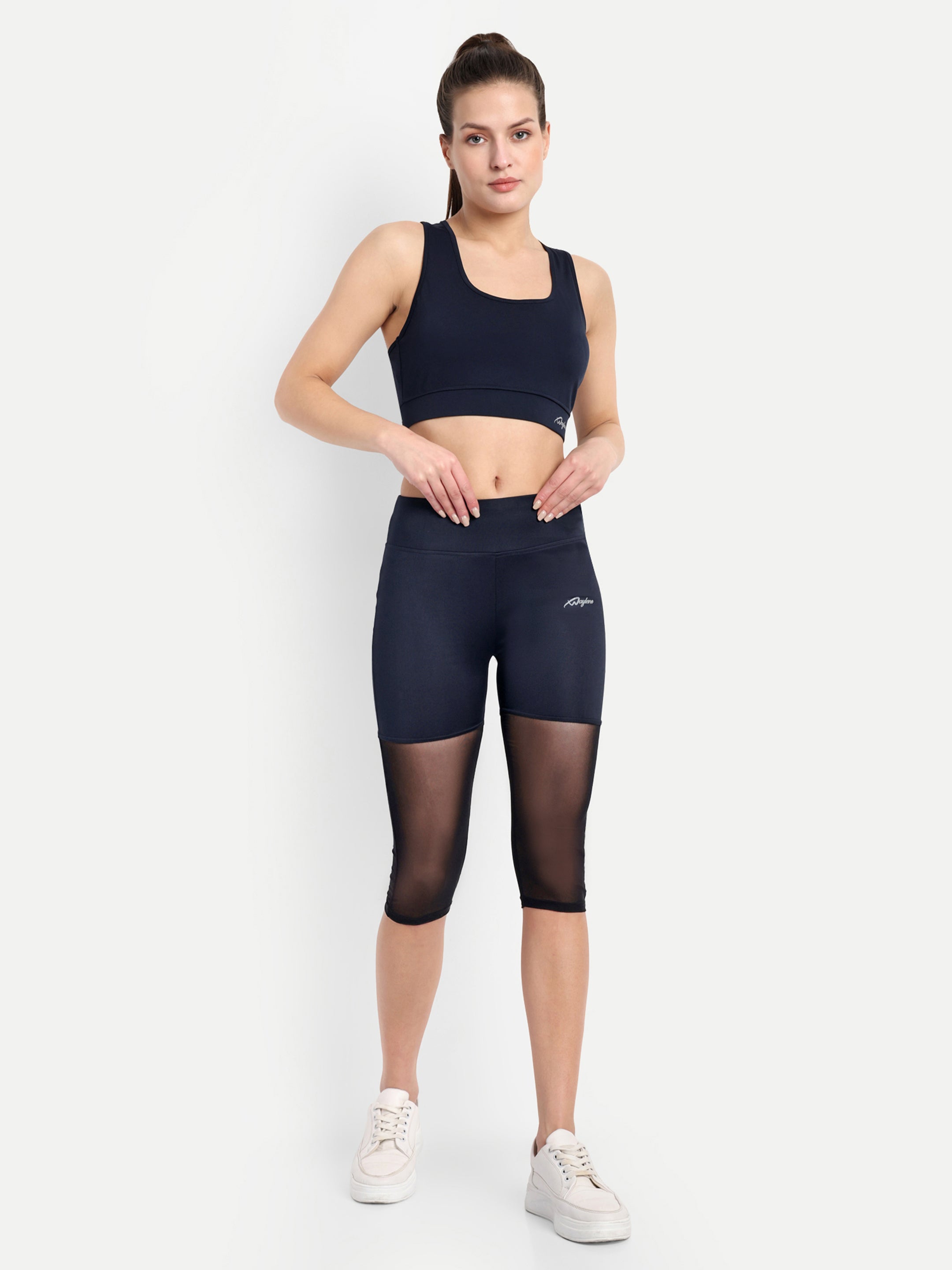 Woman wearing  Waylene navy blue high-waisted capri leggings with rounded mesh panels & sports bra