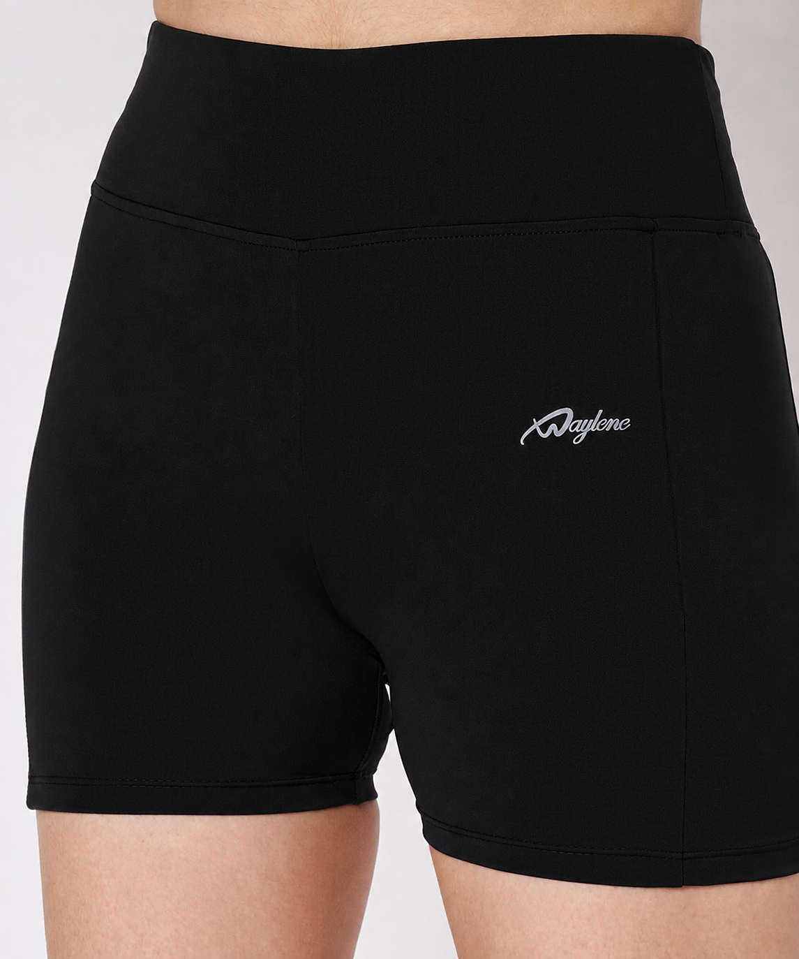 Close-up shot of Waylene black activewear shorts highlighting high waistband, flatlock seam detailing, and script logo