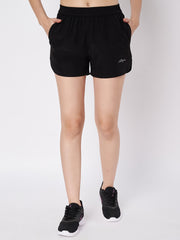 Close-up view of Waylene's black polyester shorts featuring an elastic waistband and subtle logo on the left thigh, modeled with black athletic shoes, emphasizing comfort and style for active wear.