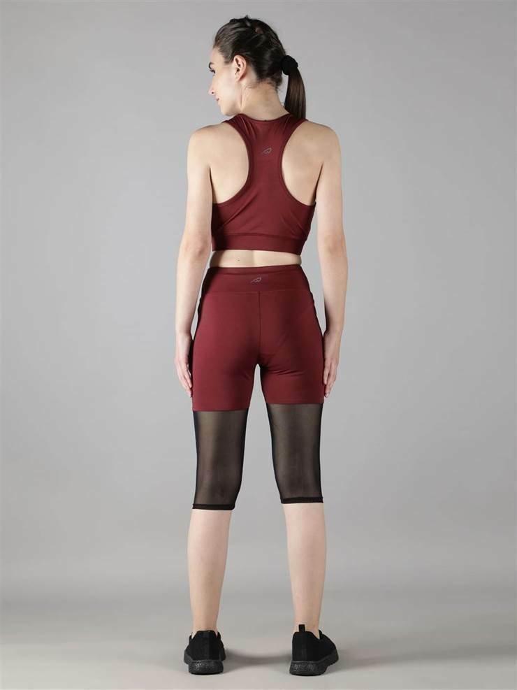 Woman wearing Waylene maroon (wine) high-waisted capri leggings with rounded mesh panels and sports bra back view